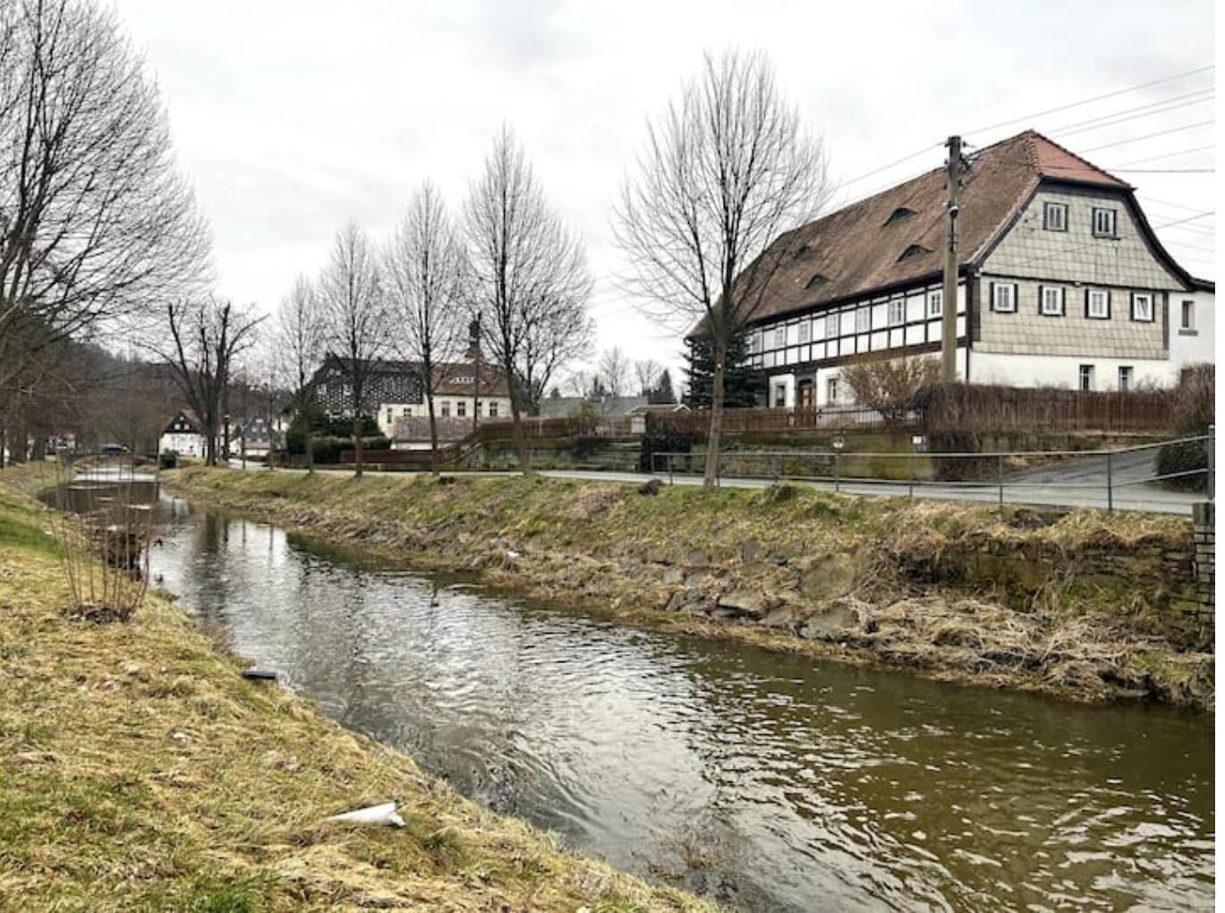 A riverside view with a building featuring a traditional half-timbered facade.