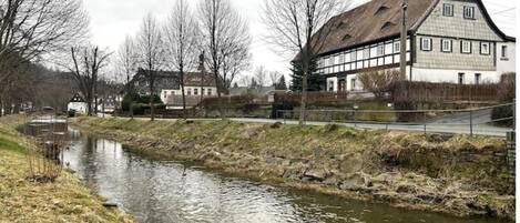 A riverside view with a building featuring a traditional half-timbered facade.