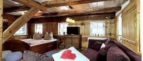 A cozy cabin interior with a loft bed, a sofa, and a television.