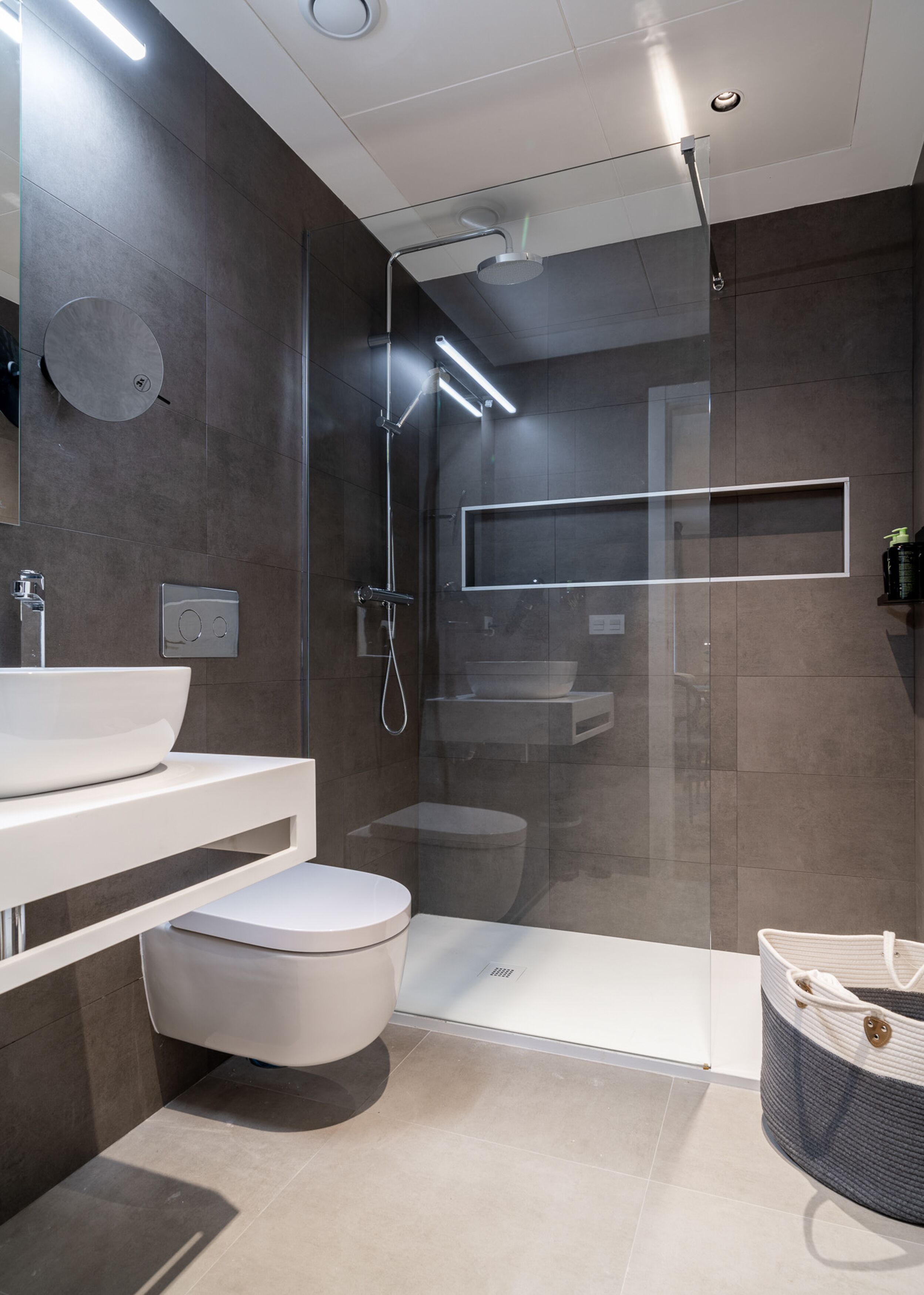 Un baño moderno con ducha de vidrio, lavamanos blanco y un inodoro.