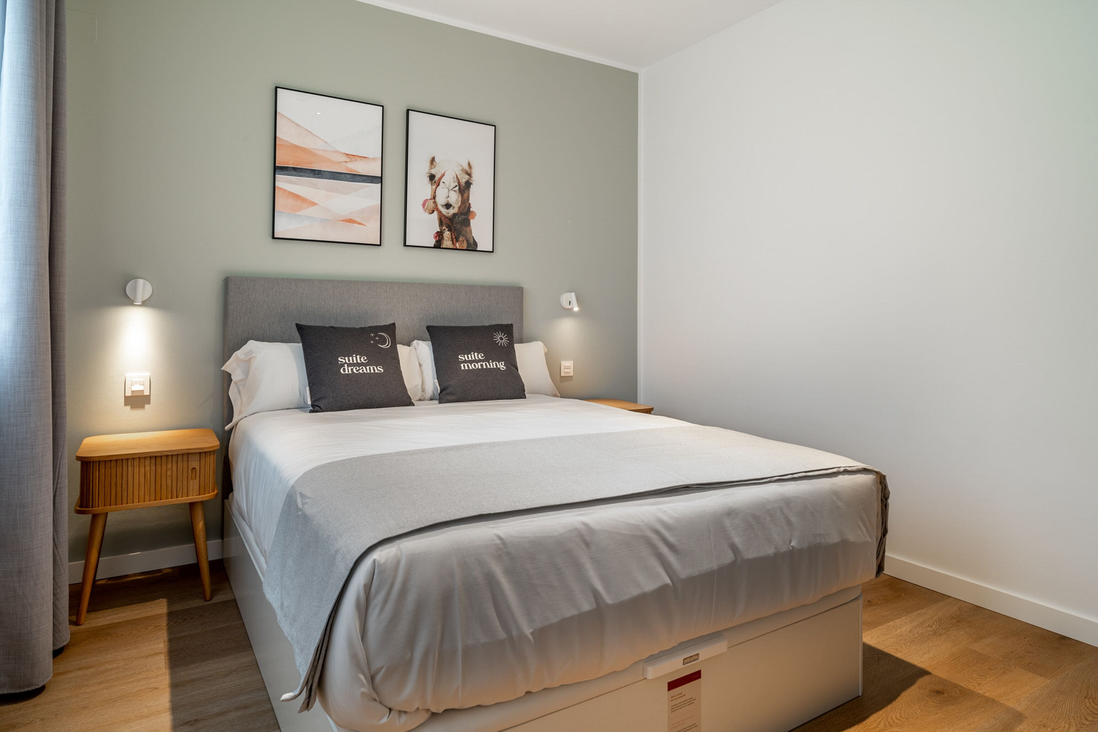 Een keurig opgemaakt slaapkamer met een groot bed, twee nachtkastjes en wandlampen.