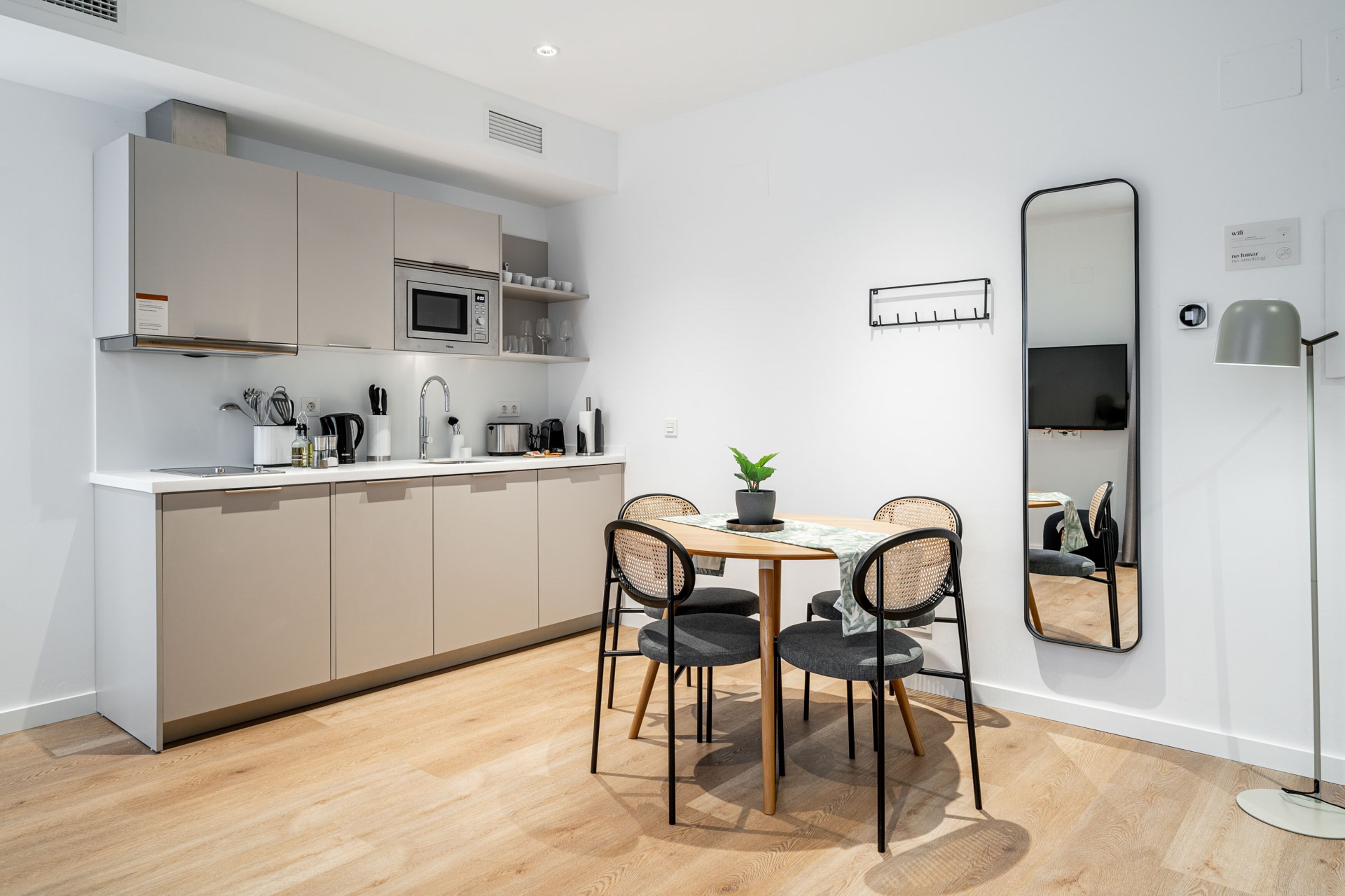 Una cocina moderna con armarios blancos, un microondas y un comedor con mesa y sillas.