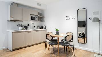 Una cocina moderna con armarios blancos, un microondas y un comedor con mesa y sillas.