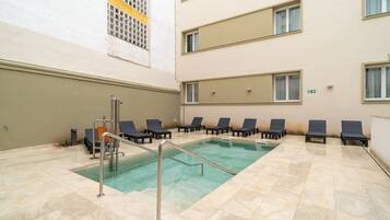 Zona de piscina con sillones de descanso y barandilla de seguridad metálica.