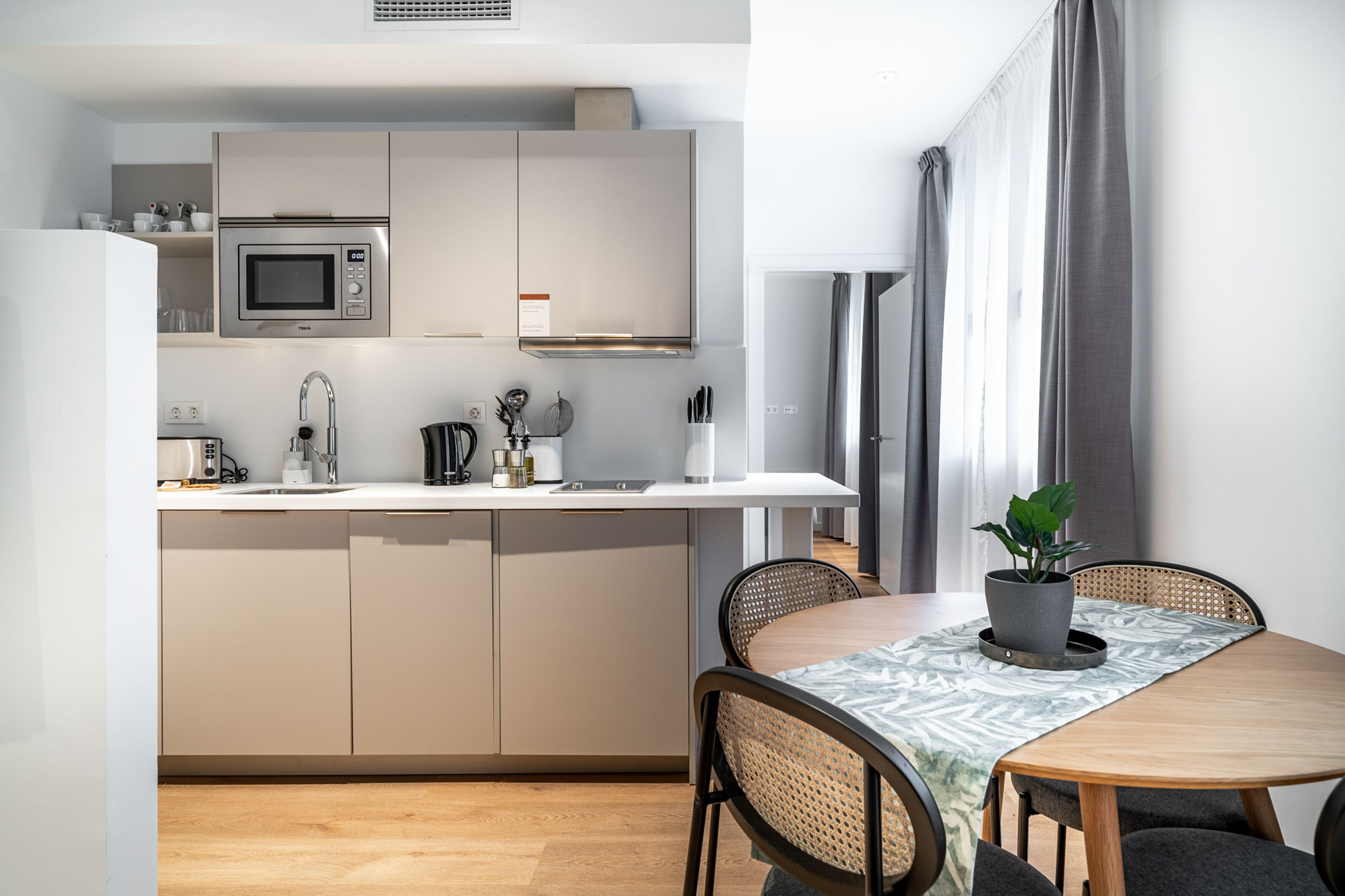 A modern kitchen with a microwave, sink, and dining area with a table and chairs.