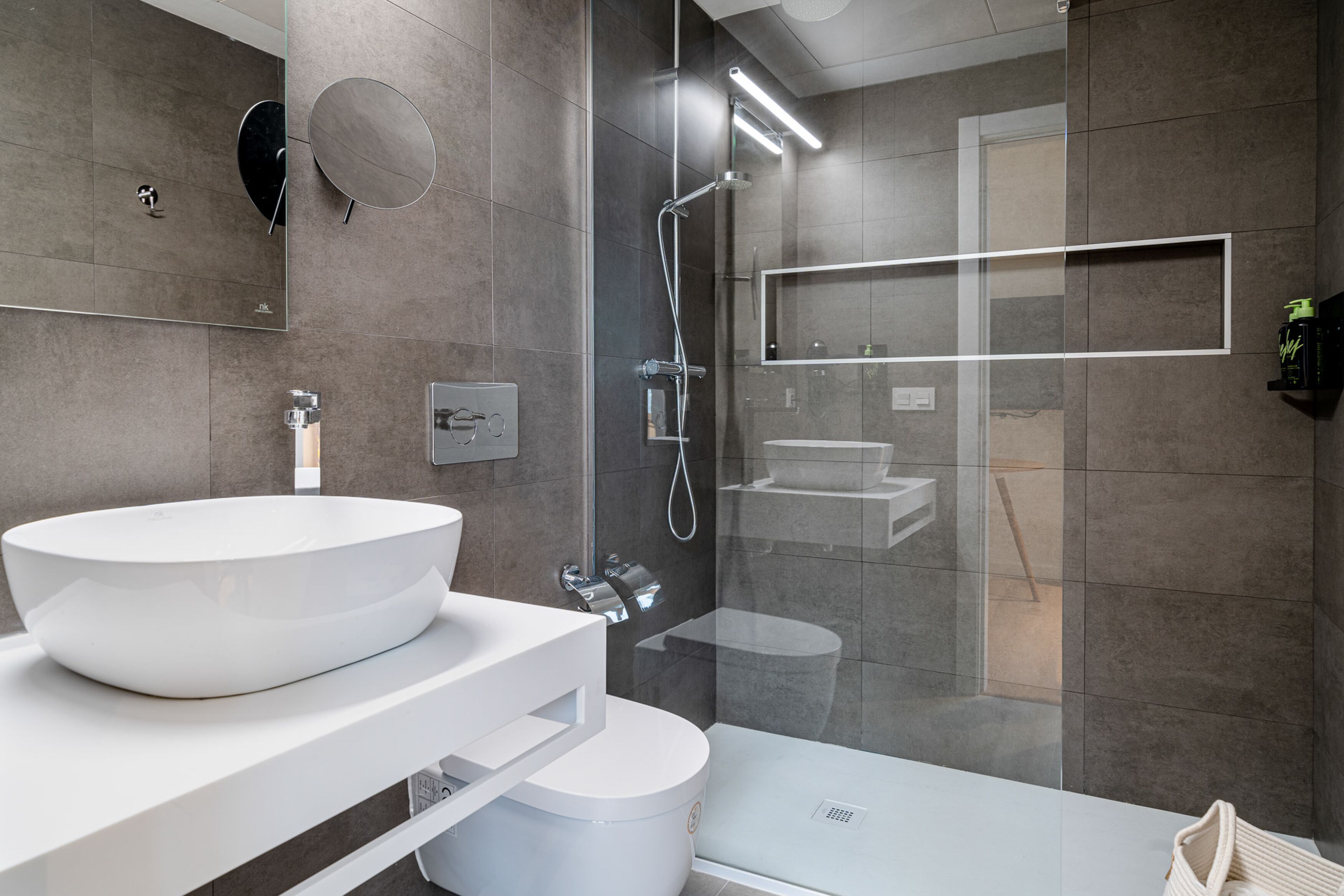 Une salle de bain moderne avec un grand lavabo blanc, une douche à parois de verre et une baignoire blanche.