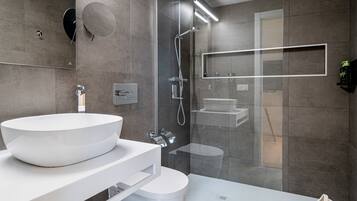 Une salle de bain moderne avec un grand lavabo blanc, une douche à parois de verre et une baignoire blanche.