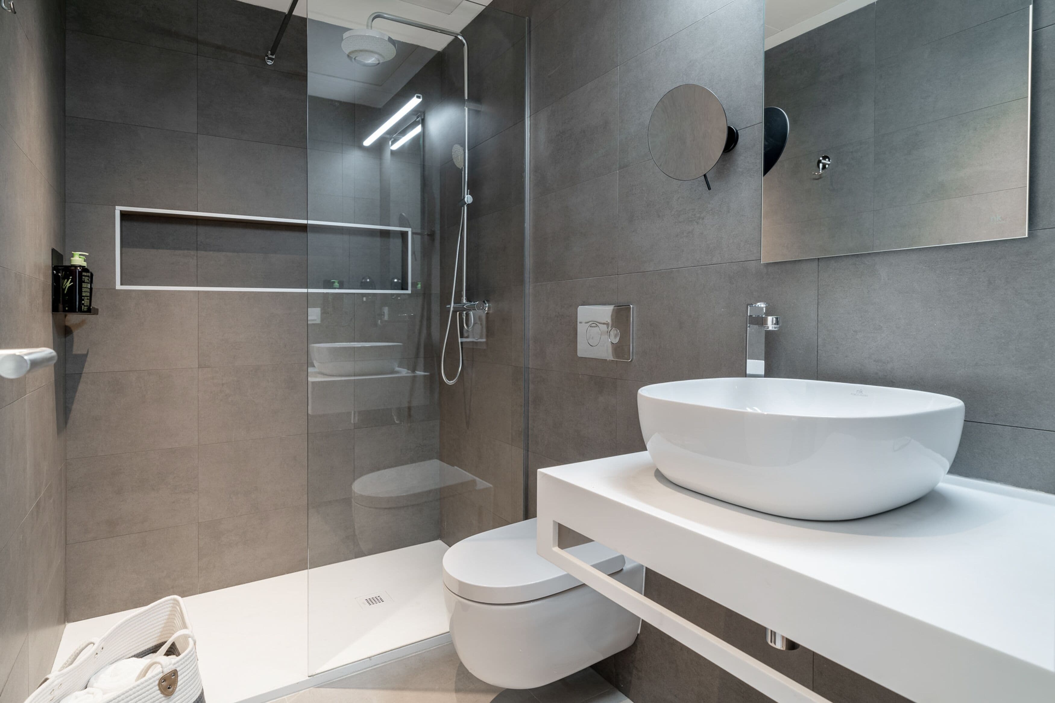 Un baño moderno con un lavamanos grande de color blanco, una cabina de ducha de vidrio y un inodoro.