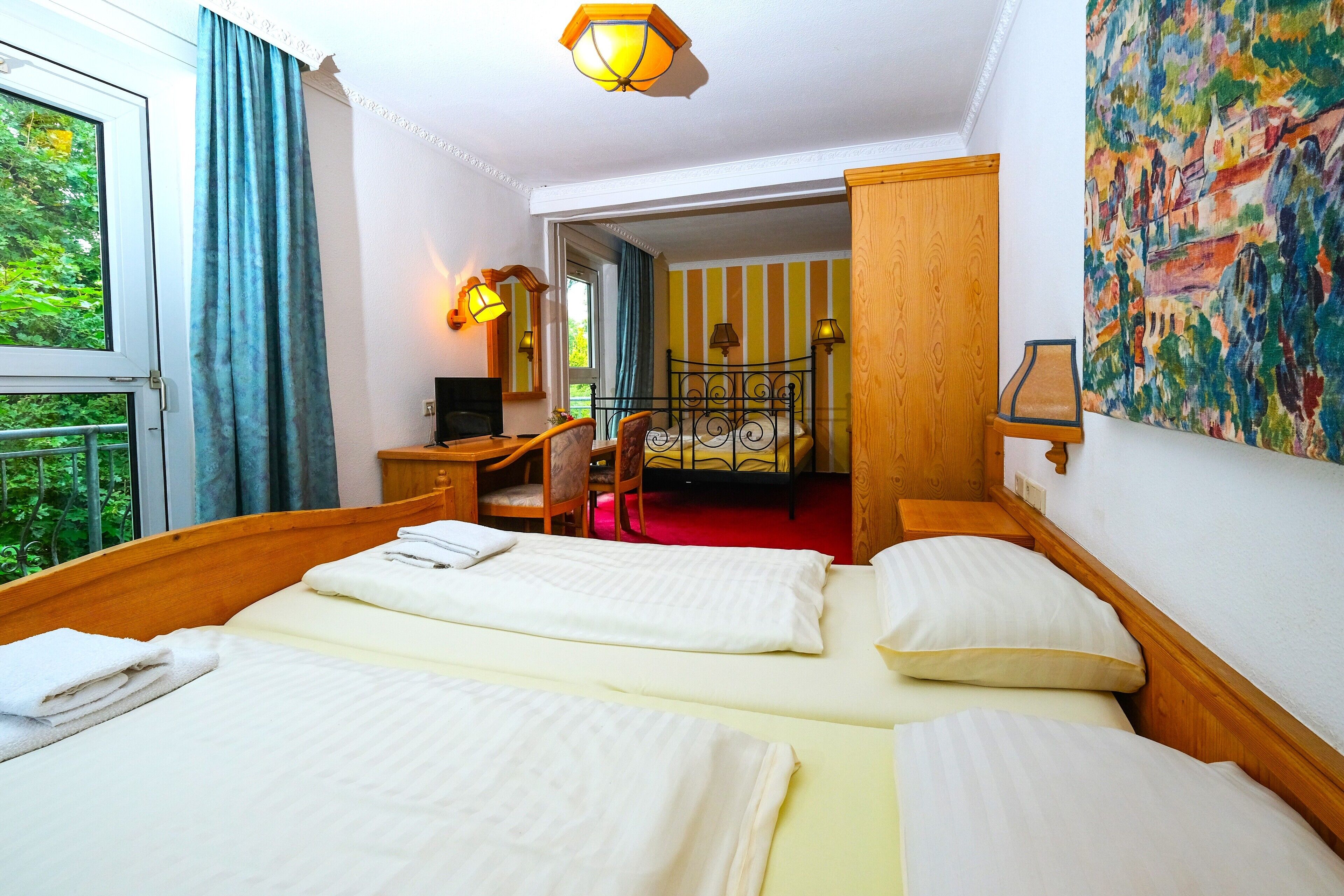 Een hotelkamer met twee bedden, een bureau, een stoel, een televisie en een schilderij aan de muur.