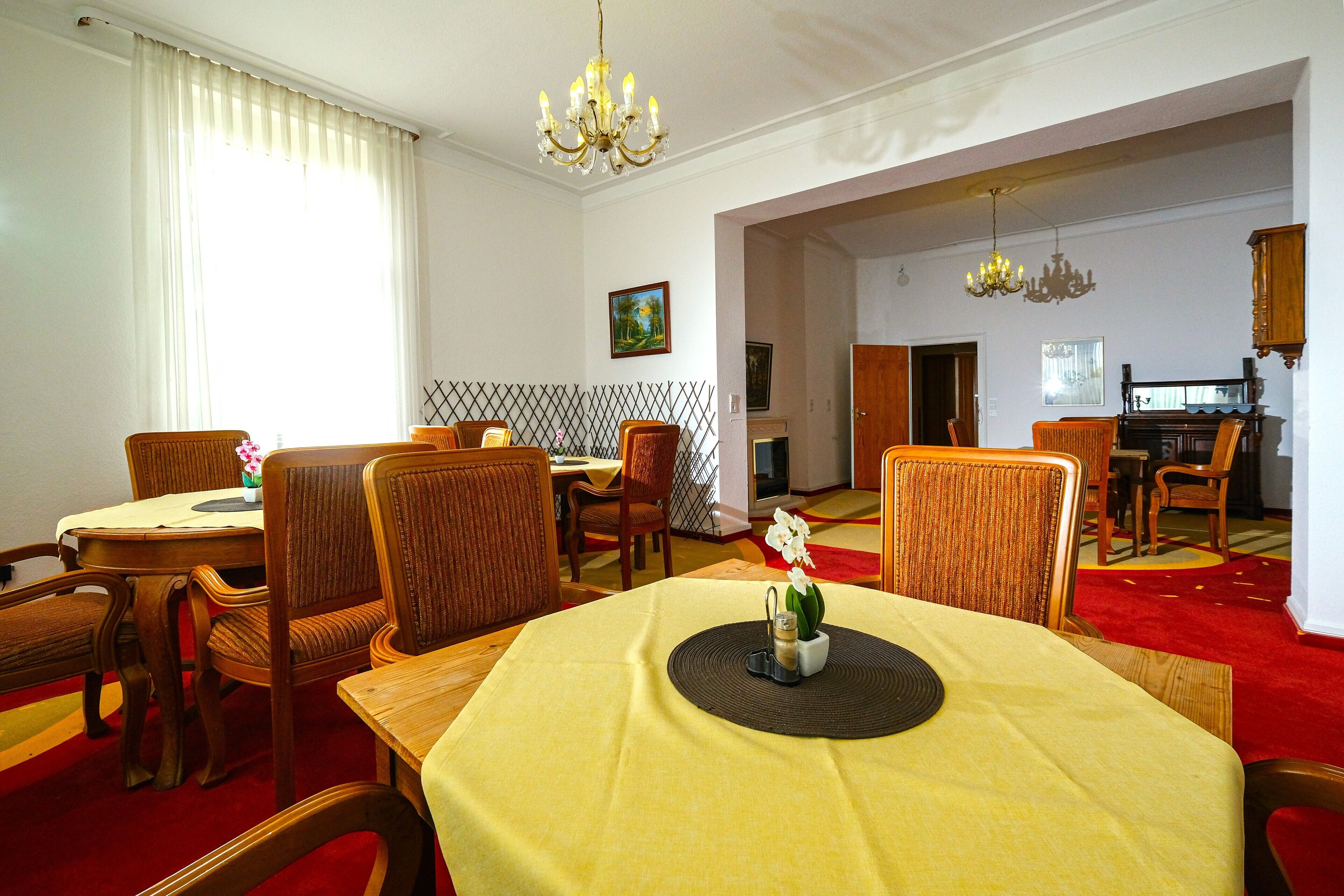 A dining area with a round table, chairs, and a chandelier.