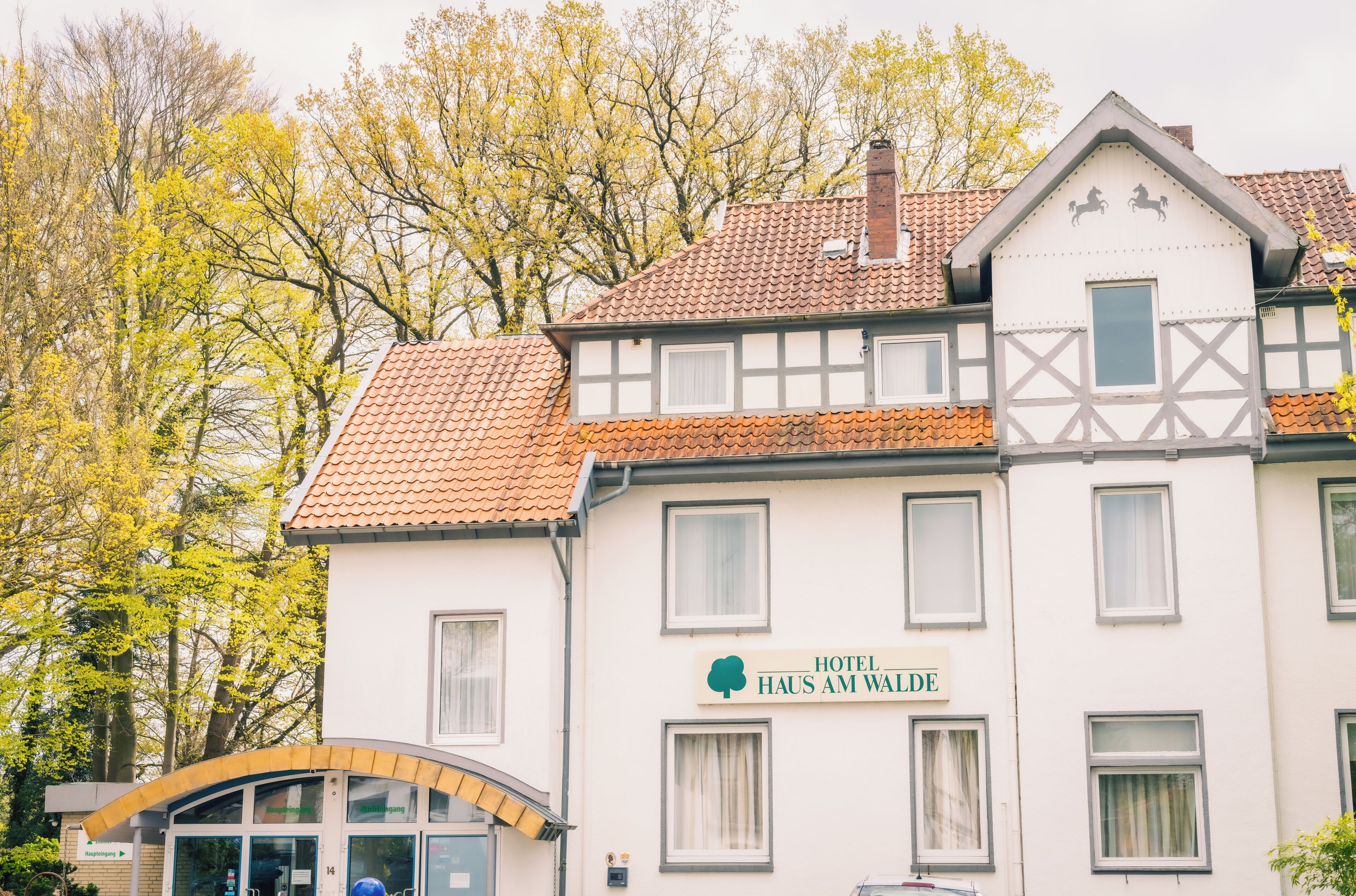 A traditional European hotel with a sign reading "Hotel Haus Am Walde".