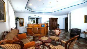 A spacious living area with a large sofa, armchairs, a coffee table, and a wooden cabinet. - Hotel Haus Am Walde (Bad Fallingbostel)