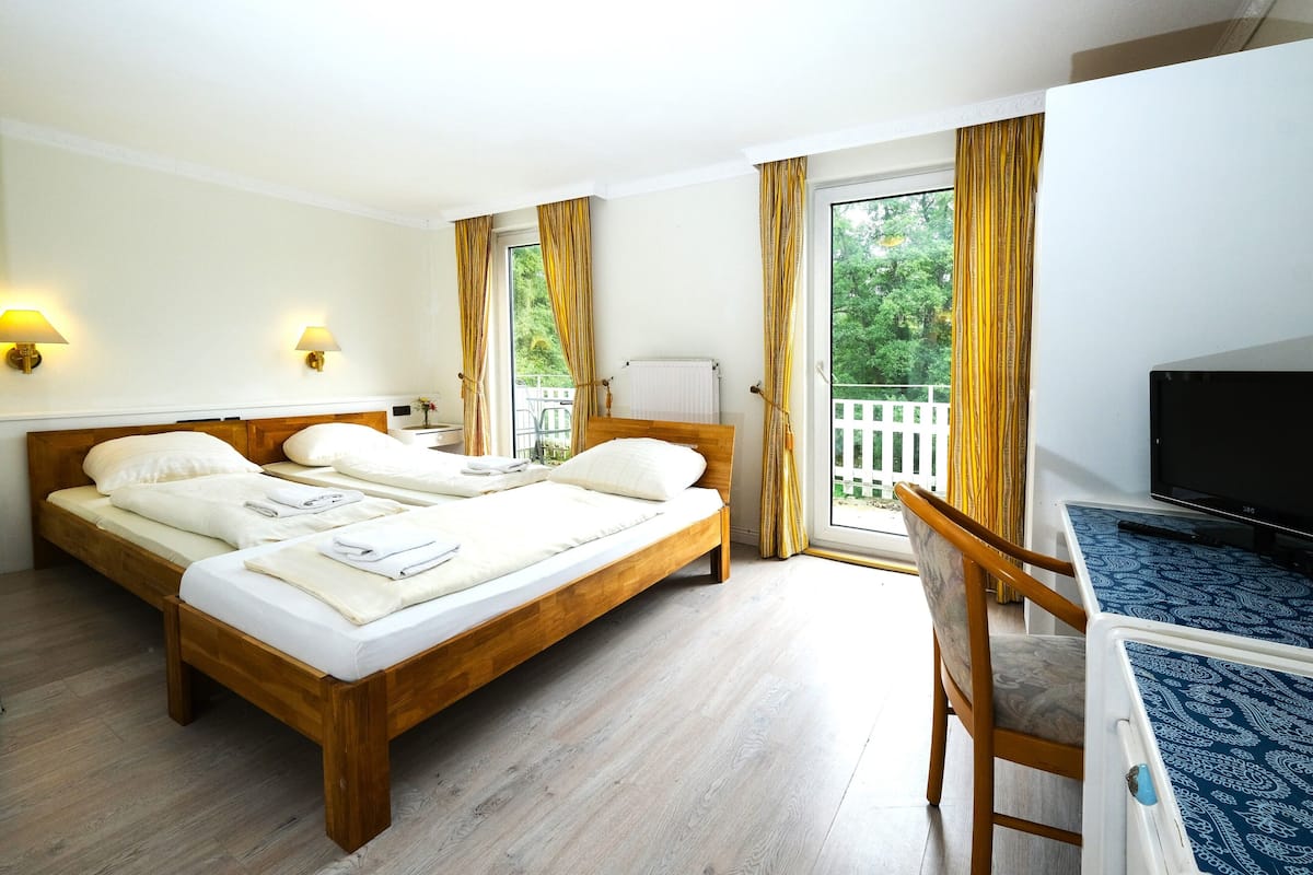 Uma cama de casal com lençóis brancos, cabeceira de madeira e duas luminárias de apoio.