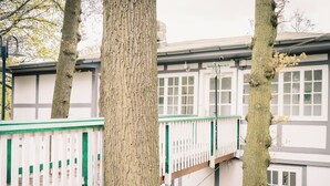 A multi-story building with white and grey exterior walls, large windows, and a balcony with a white railing. - Hotel Haus Am Walde (Bad Fallingbostel)