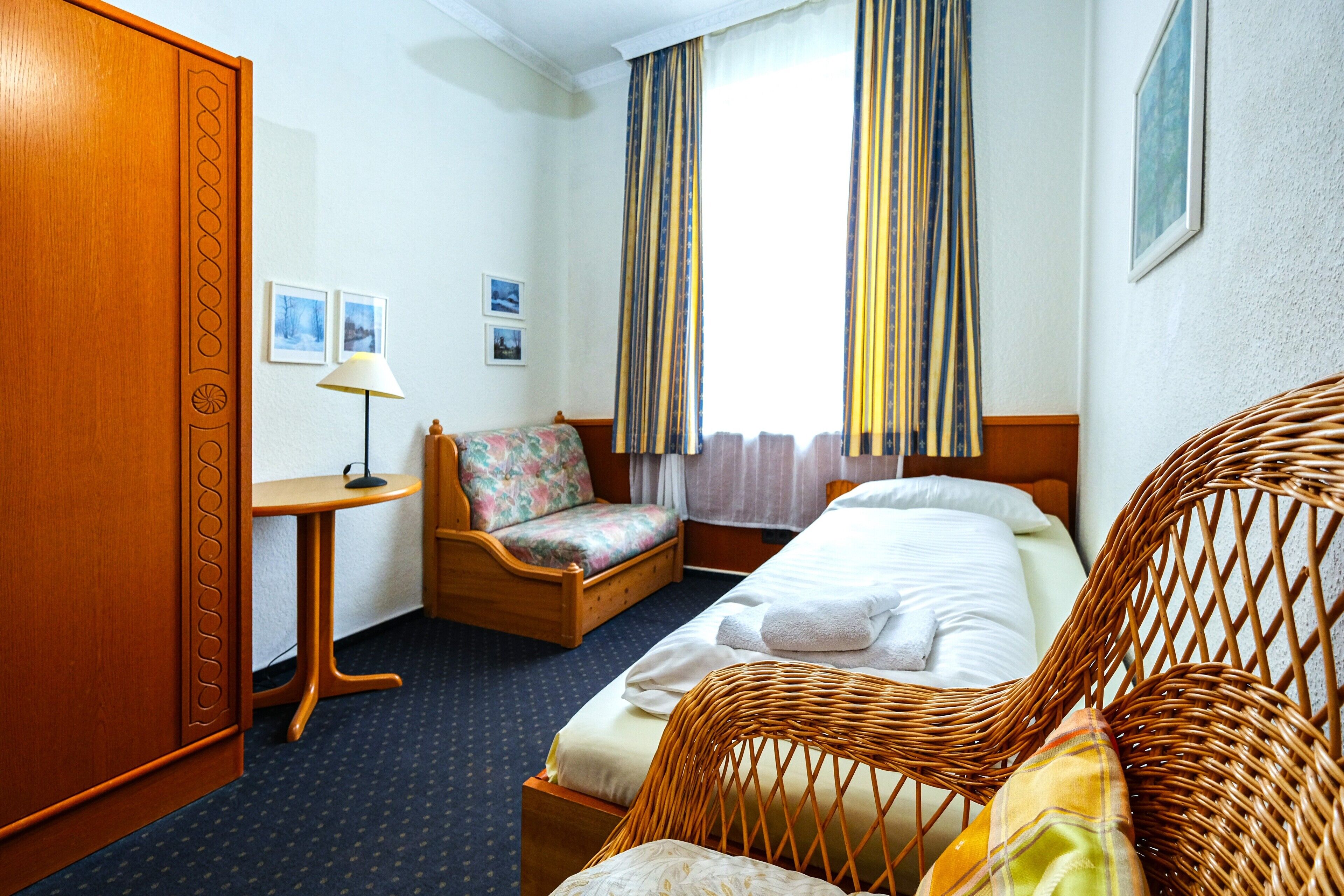 Una habitación de hotel con una cama, una silla, un escritorio y un armario.