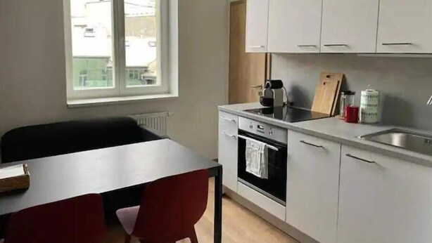 A modern kitchen with white cabinets, a black countertop, and a window above the sink. - Brand New Apartments 4.1 (Hlavní mesto Praha)