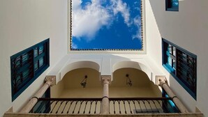Una escalera con vista a un cielo despejado, paredes blancas y marcos de ventana azules.