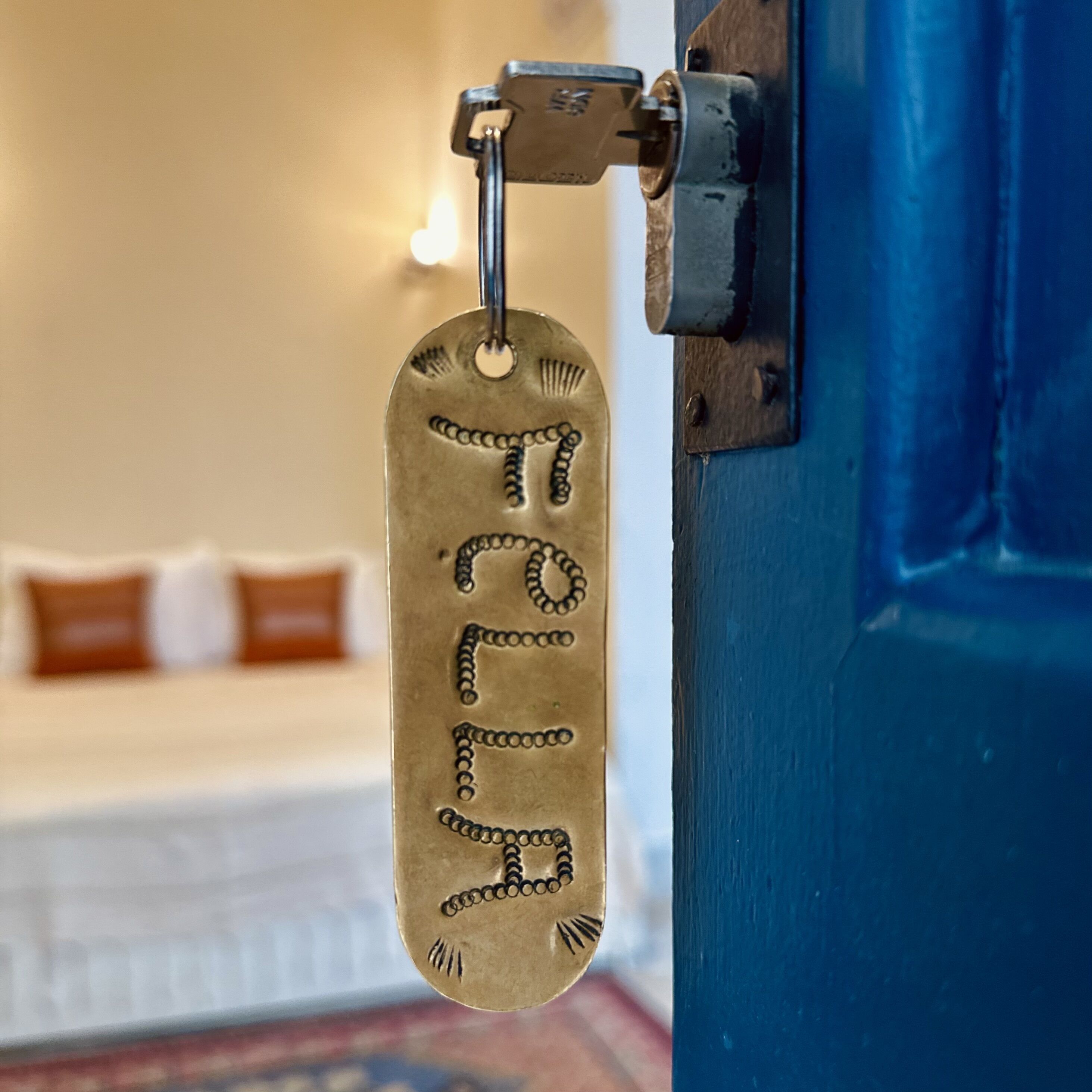 A brass tag with the number "7" attached to a blue door, likely indicating room number or a similar identifier.