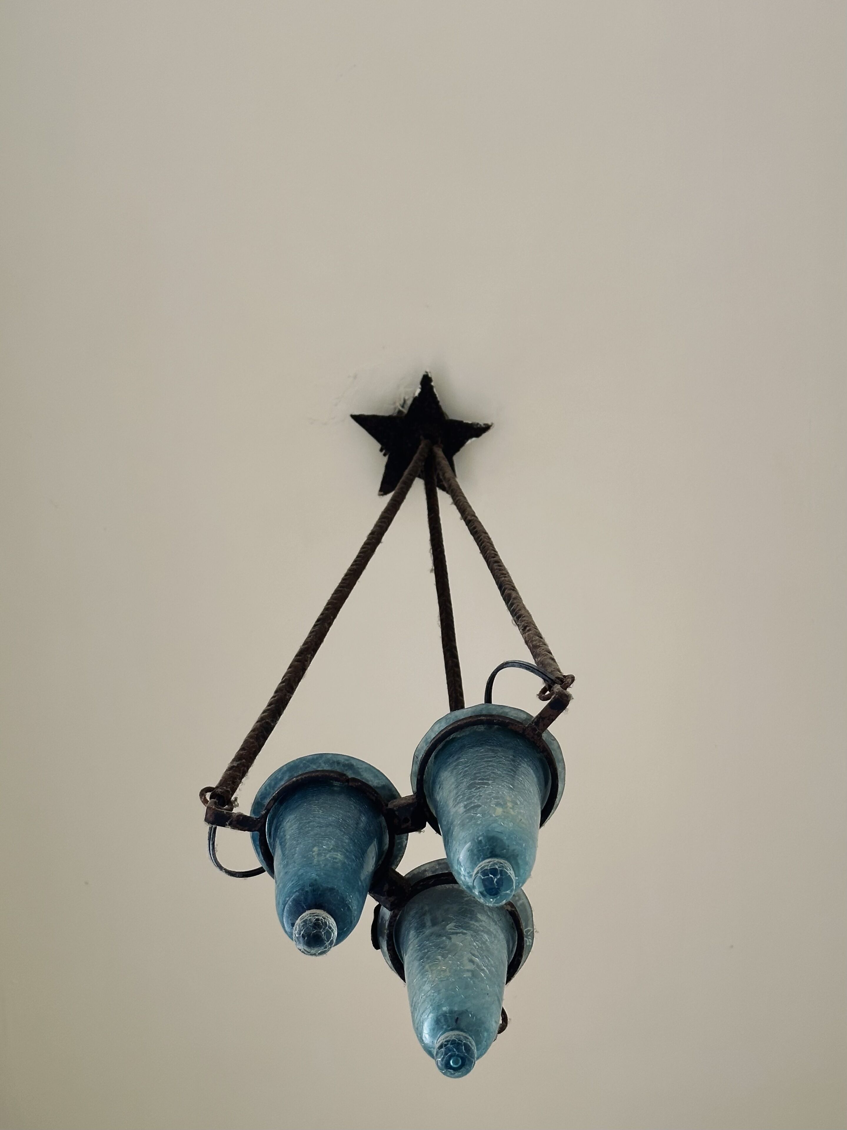 A ceiling-mounted chandelier with three blue glass shades and a star-shaped mount.