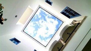 Una habitación con un tragaluz grande, una ventana pequeña y un balcón con barandilla.