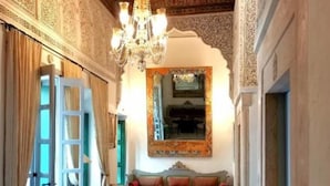 Una habitación con candelabro, un conjunto de sofás y una alfombra estampada.