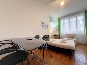 Cozy retreat with a single bed, dining table, and desk, perfect for a relaxing stay.