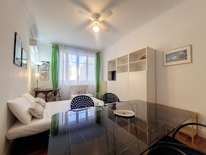 Cozy space with a glass dining table, comfortable sofa, and large window with sheer curtains.