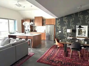 A modern kitchen with a central island, wooden cabinets, and a stainless steel refrigerator.