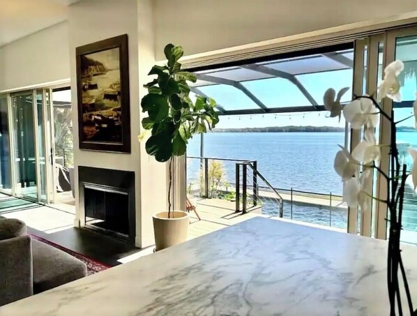 A modern living room with a fireplace, large windows, and a view of the water.