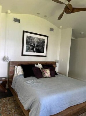 A bedroom with a wooden bed, a ceiling fan, and a framed picture on the wall.