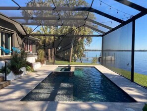 A swimming pool with a glass enclosure, surrounded by a deck and a view of a lake. - LAKEHOUSE RETREAT, a lakefront villa with pool & hot tub close to beaches (Tarpon Springs)