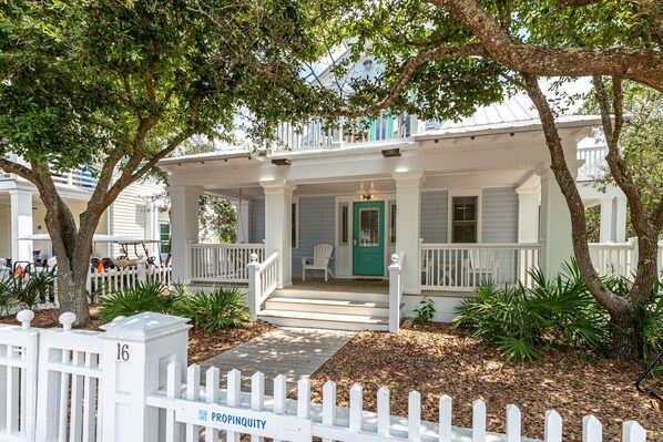 A two-story house with a porch, white picket fence, and a green door.