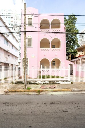 A pink building with multiple arches and a white fence in front. - 4 bedroom Miramar - 2 apt combo (San Juan)