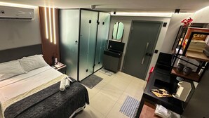 Ein Hotelzimmer mit Bett, Kleiderschrank, Schreibtisch mit Stuhl, Spiegel und Klimaanlage.
