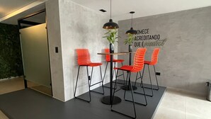 Ein moderner Essbereich mit einem Tisch, vier roten Stühlen, einer schwarzen Pendelleuchte und einer Wand mit einem motivierenden Zitat.