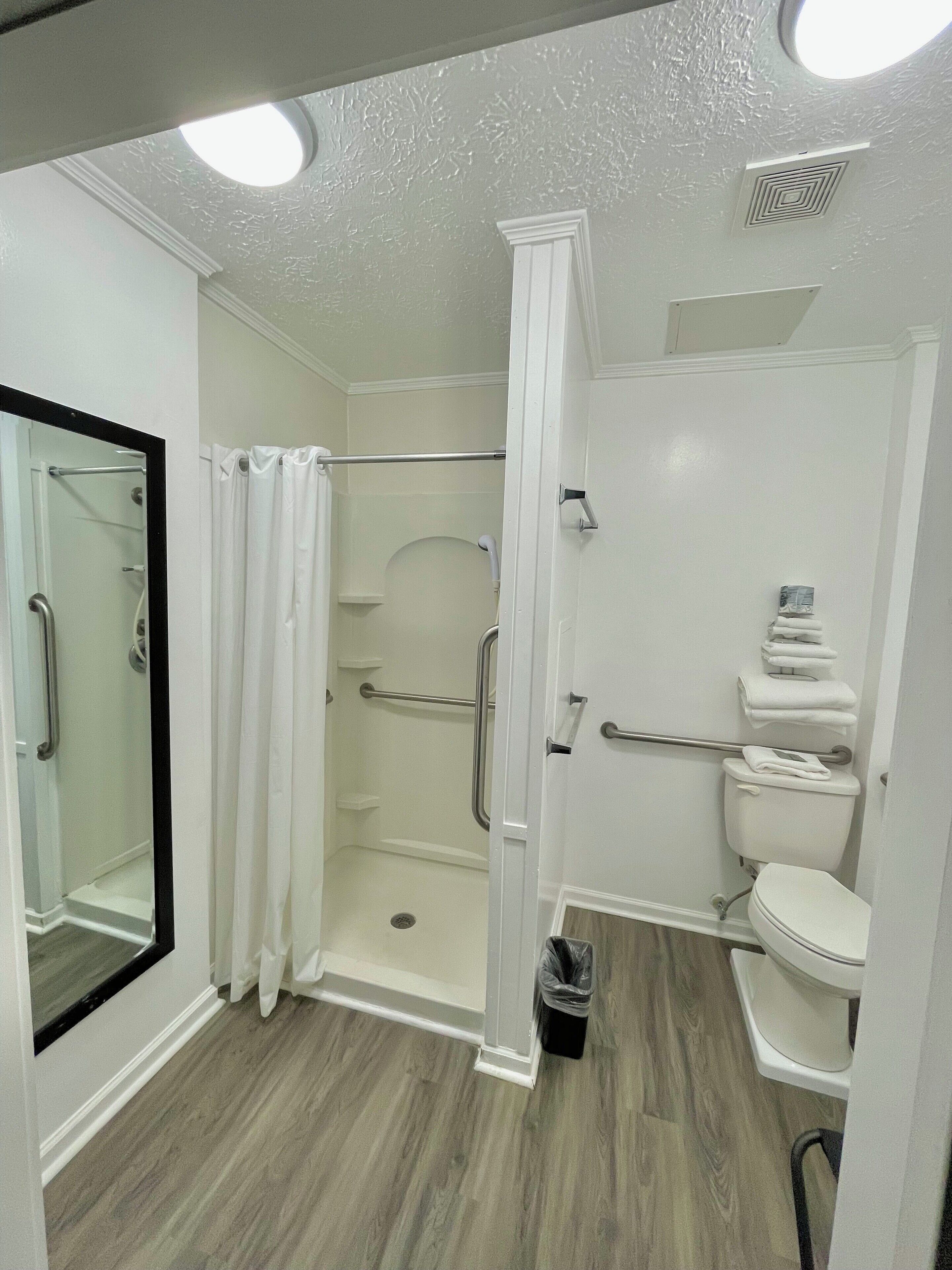 Un baño moderno con ducha a ras de suelo, inodoro y cabina de ducha con mampara de vidrio.
