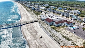 Vue aérienne d’une zone résidentielle côtière avec une jetée, des maisons et une piscine.