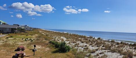 A beach view with houses, picnic tables, and a mailbox.
