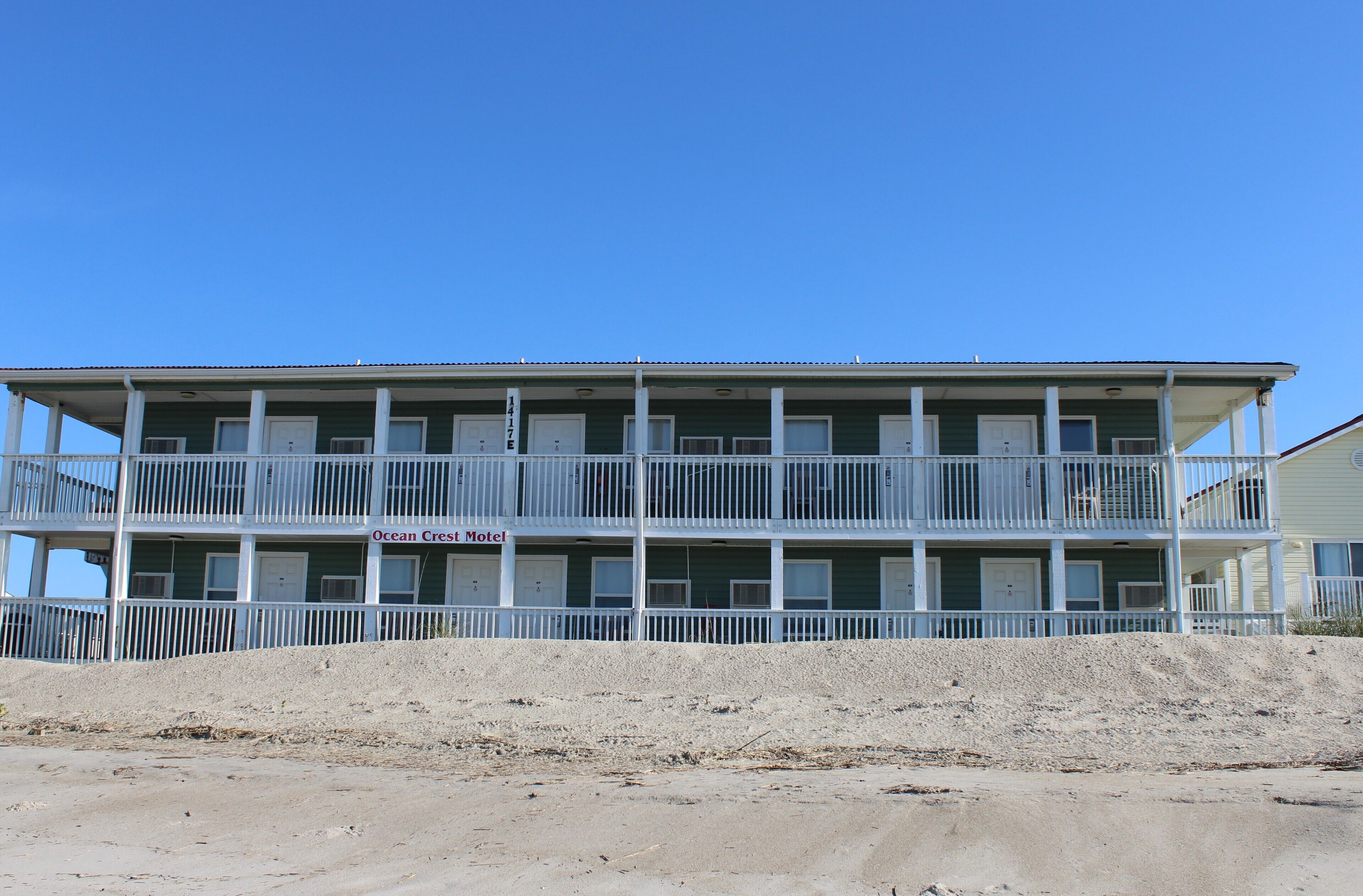 Un motel à deux étages, doté d’un balcon à chaque niveau, situé sur une plage de sable.