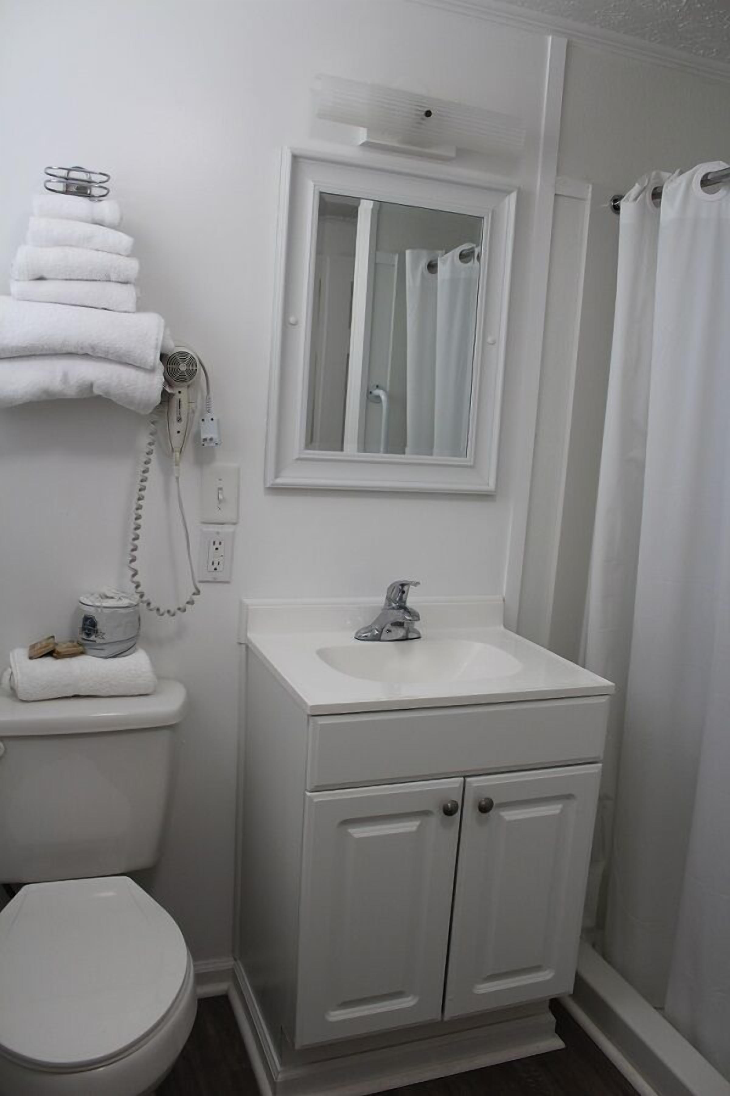 A bathroom with a white sink, mirror, and toilet.
