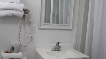 A bathroom with a white sink, mirror, and toilet.