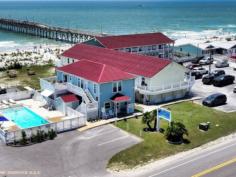 Ein Motel mit Schwimmbecken, einem Steg im Hintergrund und einem Strand in der Ferne.