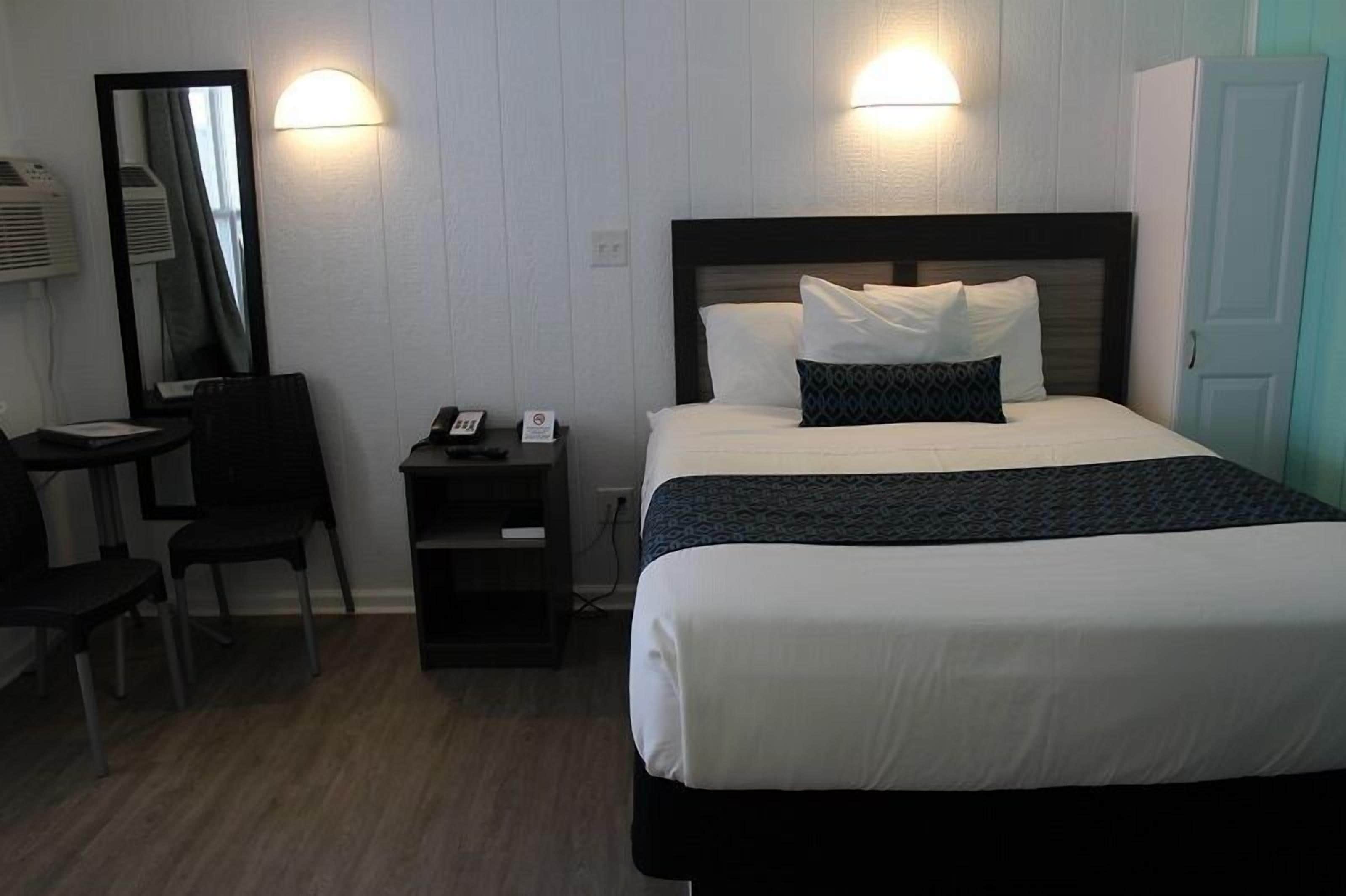 Une chambre d’hôtel comprenant un lit, un bureau, une chaise, un miroir et une armoire.