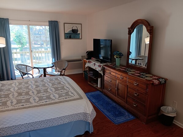 Ein Schlafzimmer mit Bett, Schminktisch, Fernseher, Stuhl und Blick ins Freie.