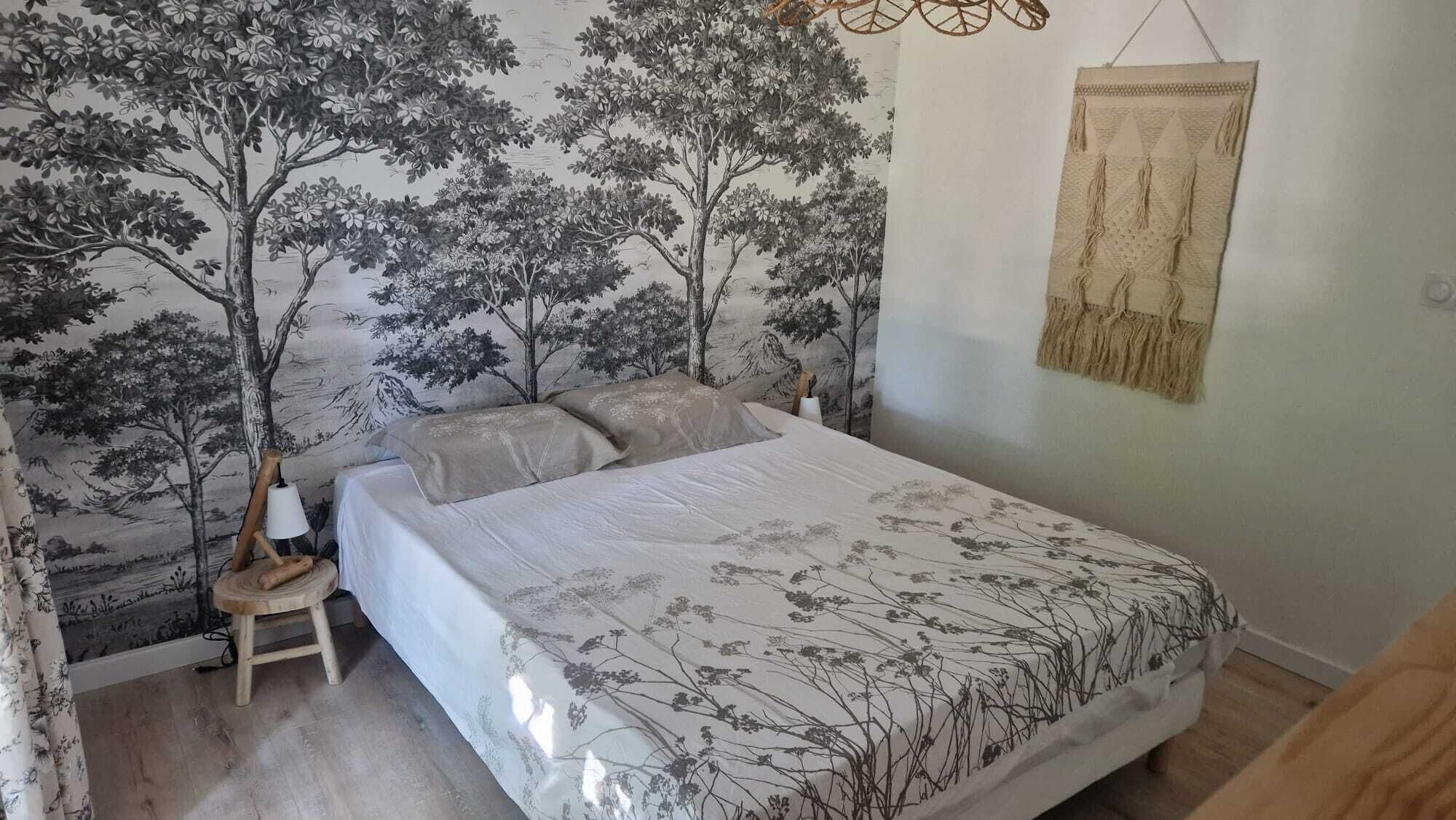 A bedroom with a bed, a nightstand, a wall tapestry, and a hanging tapestry.