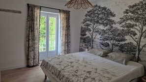 A bedroom with a bed, curtains, a window, and a wall mural.