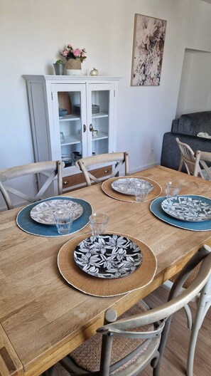 A dining table set with plates, glasses, and a vase of flowers.