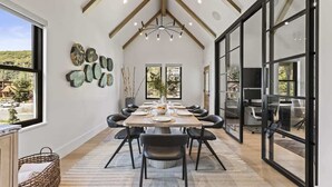 A dining area with a long table, black chairs, and a chandelier. - Abode at Hollow Mountain, private hot tub, sound system, garden (Park City)