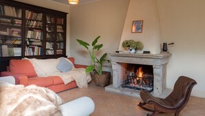 Un salon chaleureux avec une cheminée, une bibliothèque, un canapé et un fauteuil.