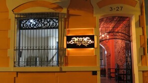 Entrada d'hotel amb una reixa de ferro forjat, un rètol de neó i una llinda de pedra.